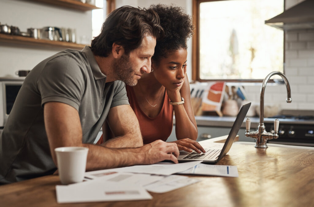 A couple looking at a laptop on a kitchen table