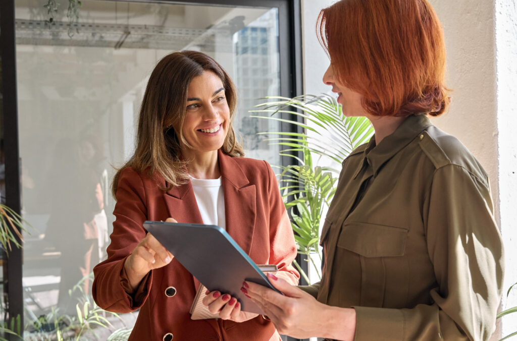 Two women talking, with one holding a digital tablet.