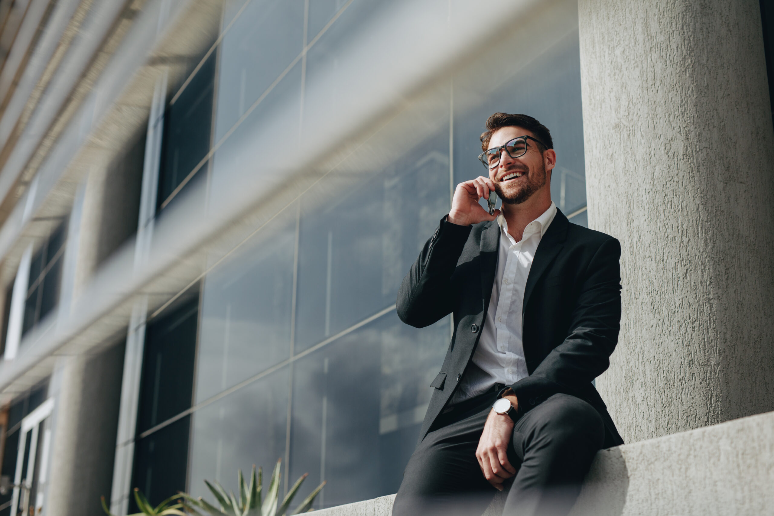 Businessman taking a break from work talking on a mobile phone sitting outdoors.