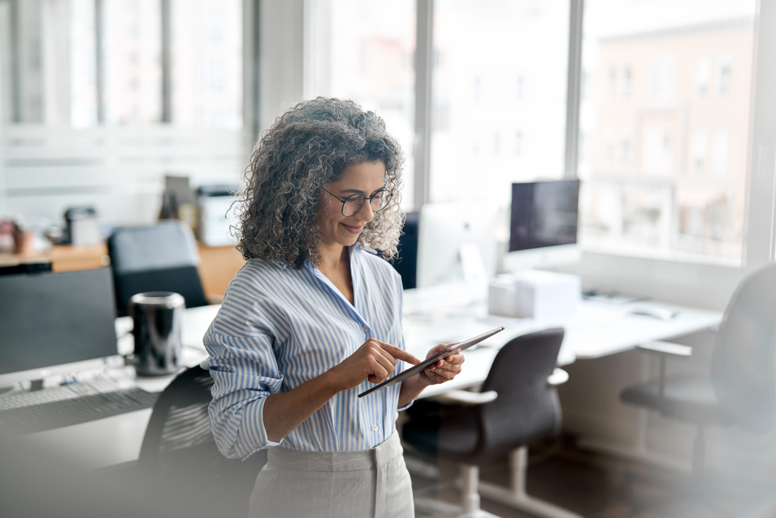 Busy middle aged professional business woman using a tablet in an office.