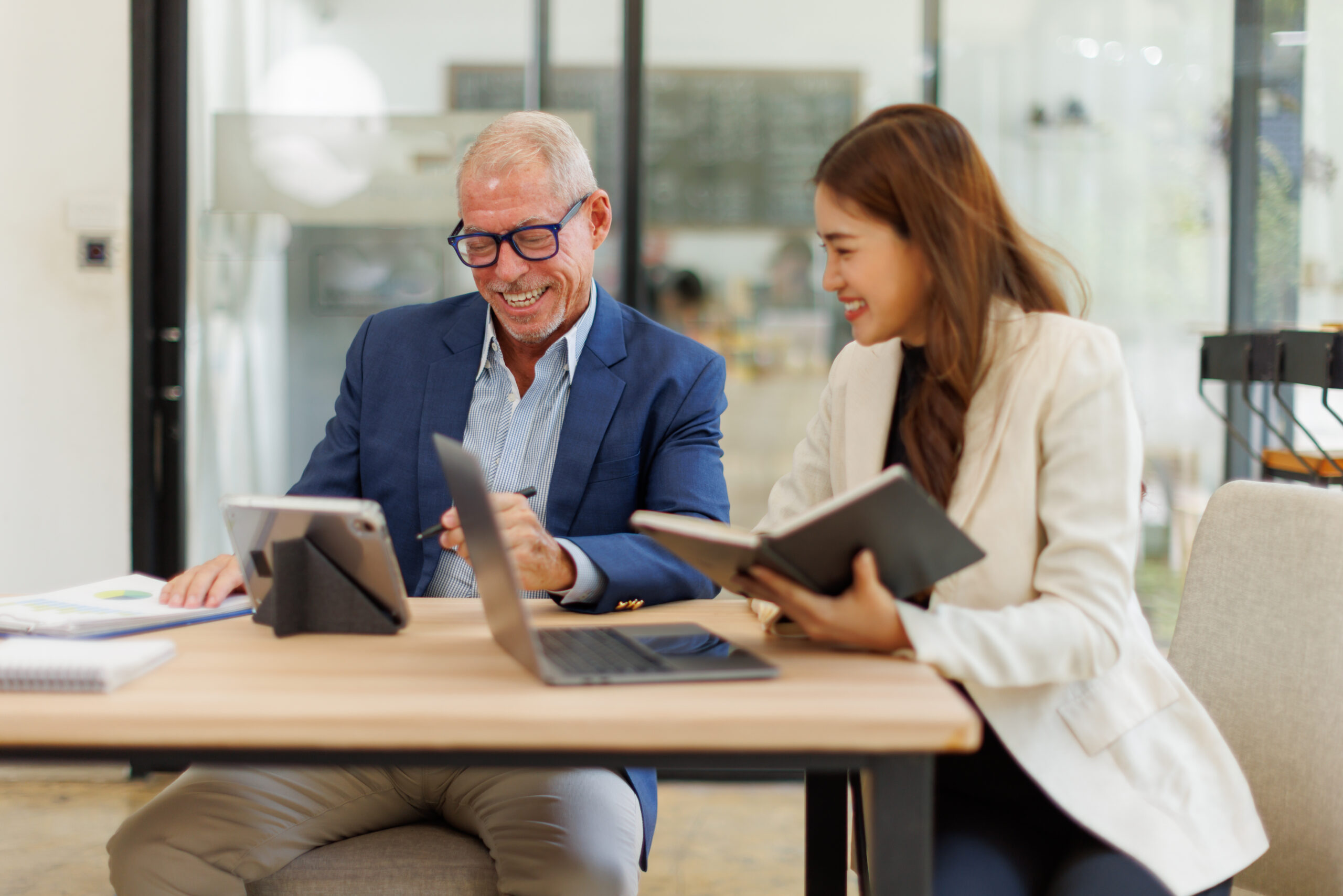 Two people sitting at a desk in a modern office, reviewing information together