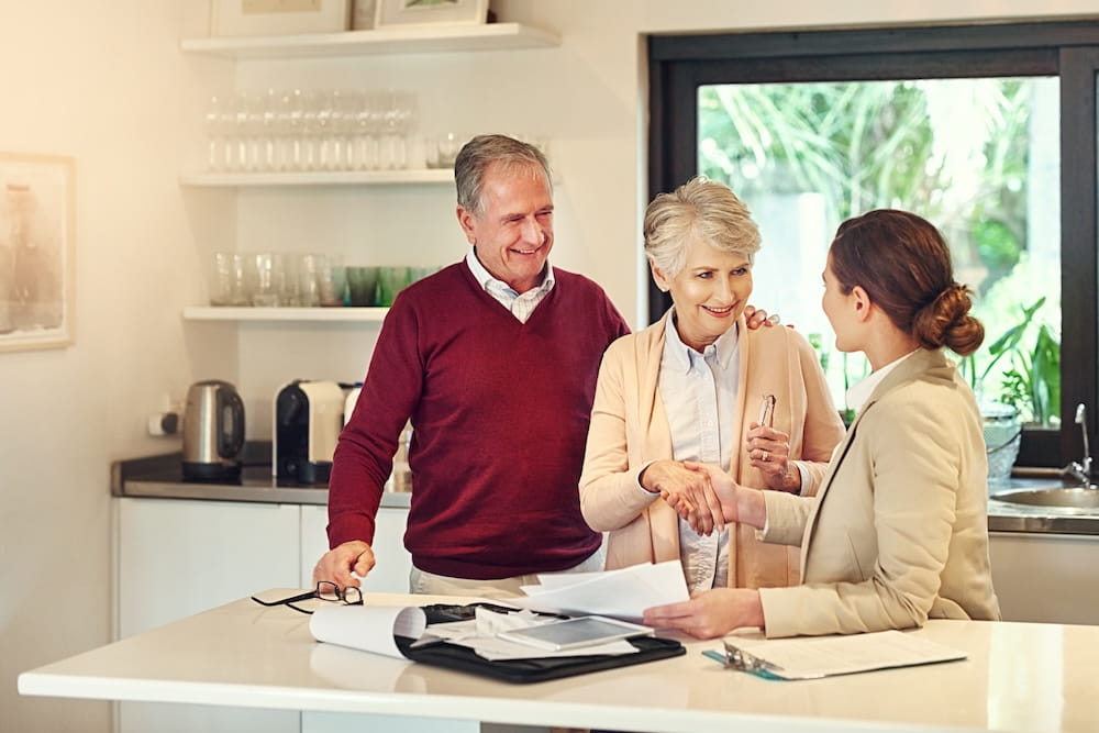 An older couple are smiling talking to their financial adviser