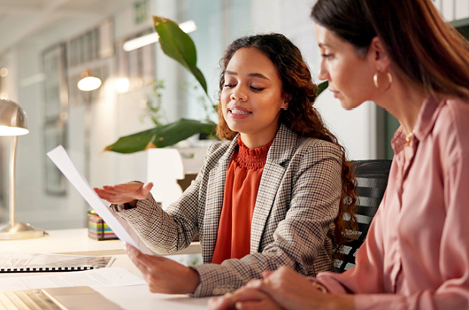 Two coworkers reviewing a document in an office